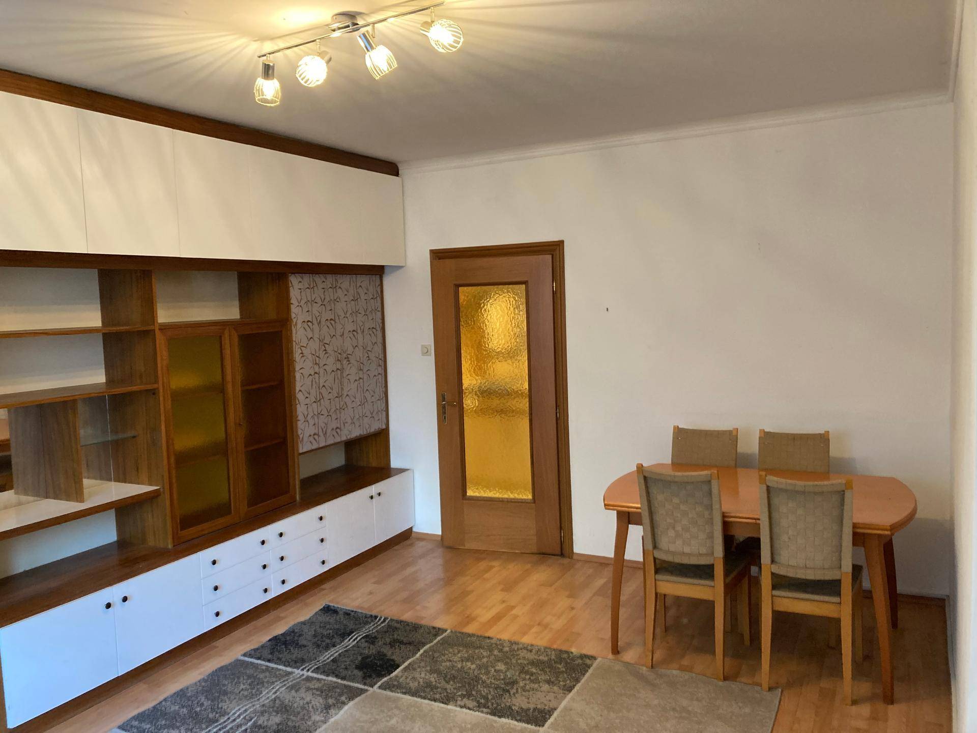 Essbereich mit Holztisch, Stühlen und einer großen, funktionalen Wohnwand.