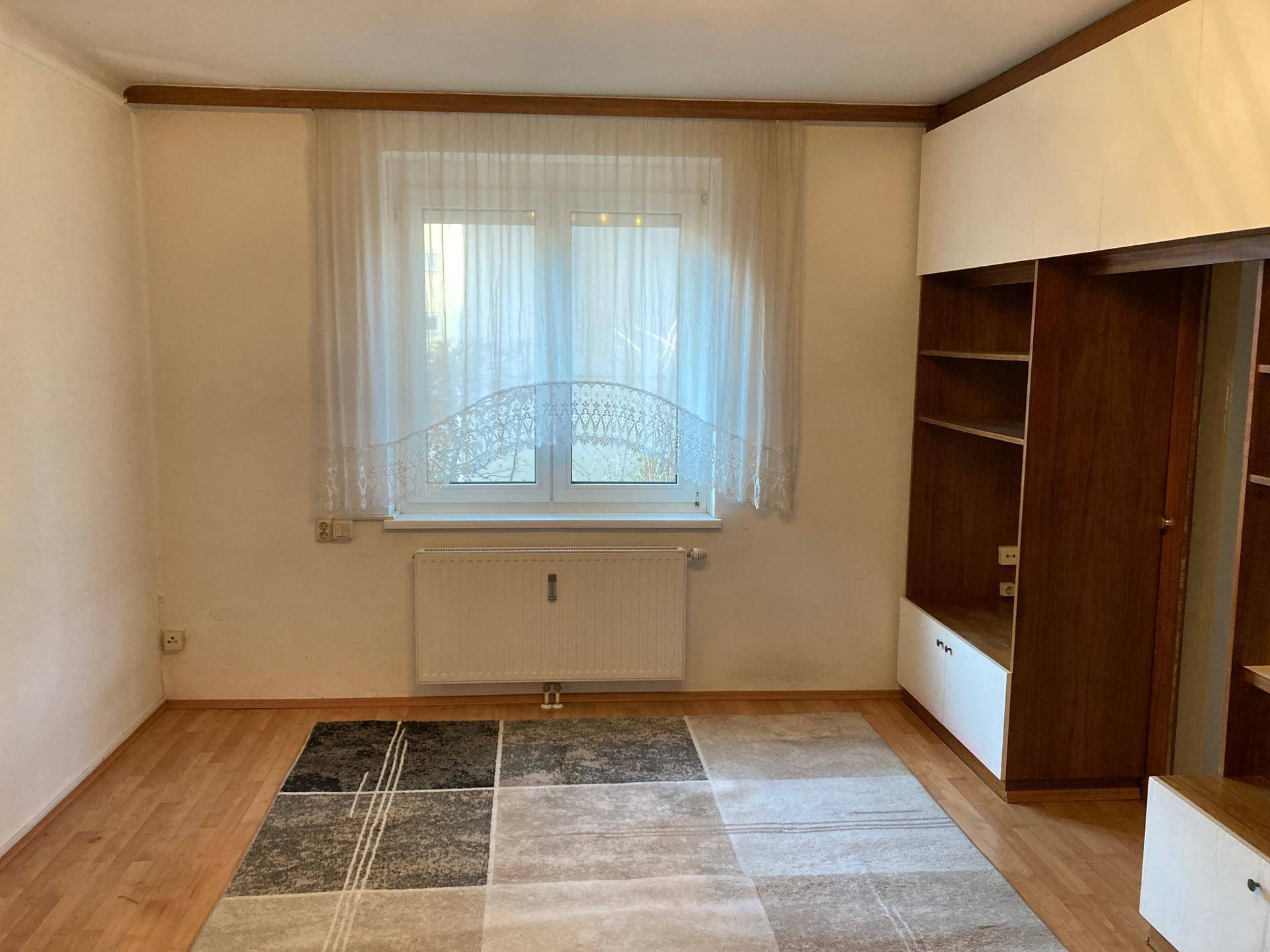 Helles Zimmer mit Holzfußboden, großem Teppich und praktischem Einbauschrank.