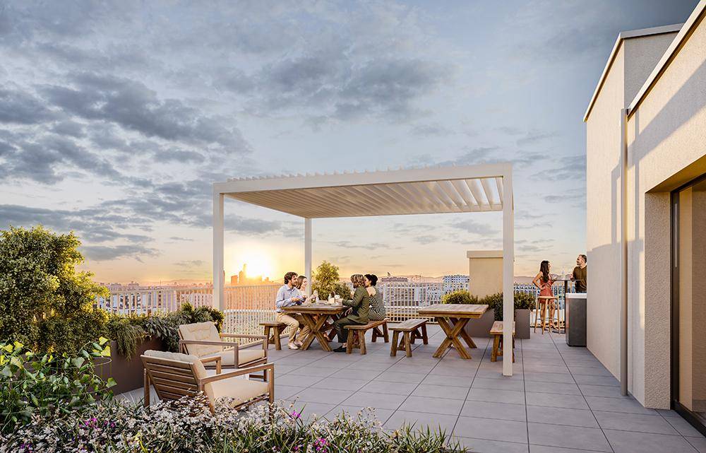 Geräumige Dachterrasse mit Essbereich unter einer Pergola und weitem Blick über die Stadt bei Sonnenuntergang.