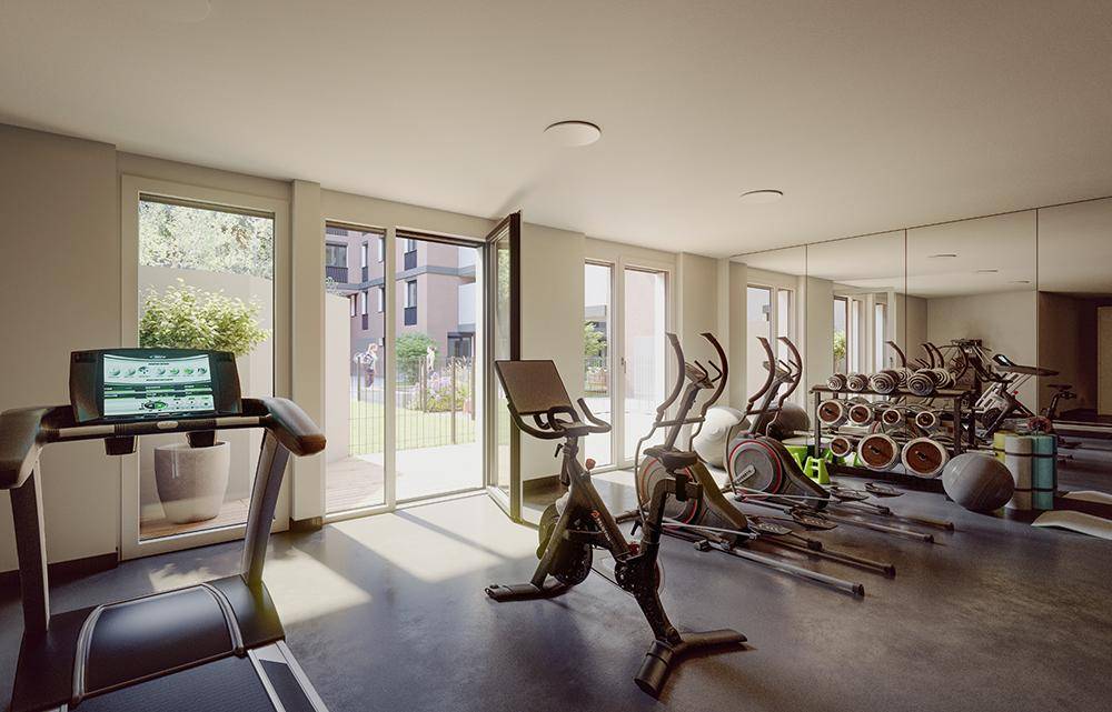 Moderner Fitnessraum mit verschiedenen Trainingsgeräten und großen Fenstern zum Außenbereich.