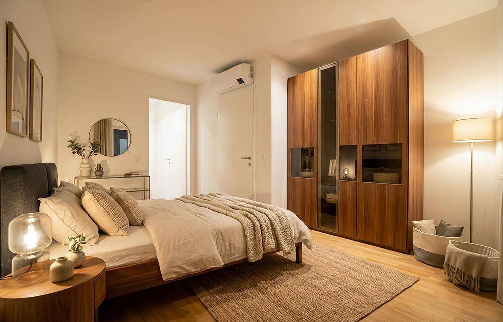 Modernes Schlafzimmer mit großem Holzkleiderschrank, Doppelbett und indirekter Beleuchtung.