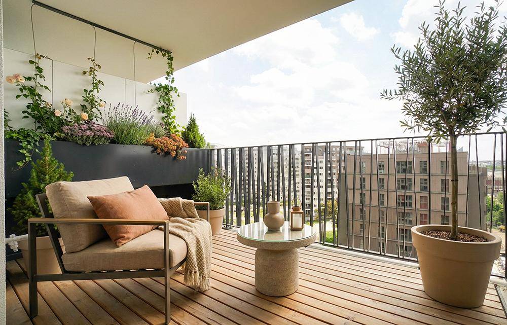 Gemütlicher Balkon mit Holzfußboden, bequemen Sitzgelegenheiten und Pflanzen für entspannte Stunden.