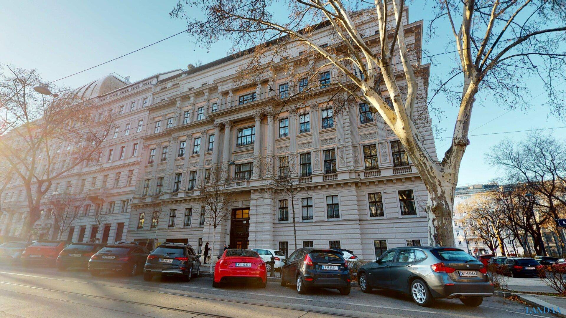 Historische Fassade eines eleganten Altbaus mit vielen Fenstern unter blauem Himmel.