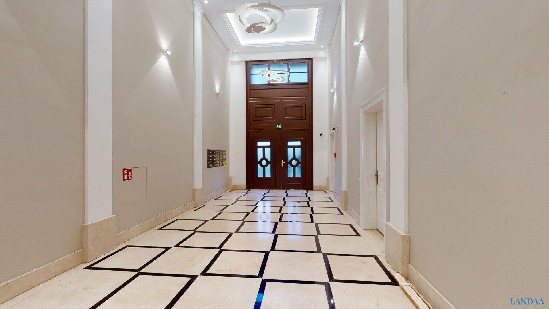 Repräsentativer Eingangsbereich mit Marmorboden, hohen Holztüren und klassischer Architektur.