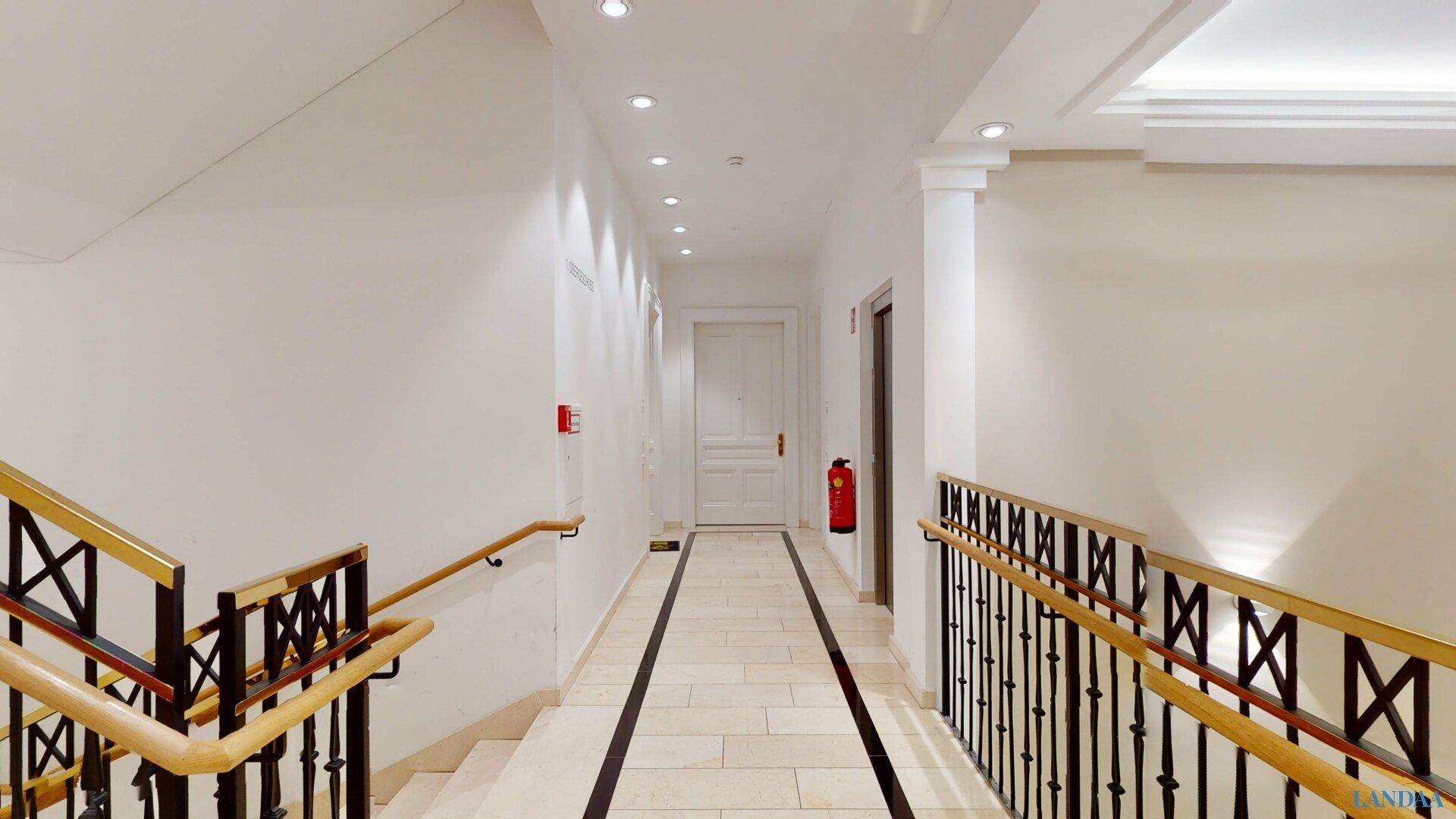 Heller Flur im Obergeschoss mit Fliesenboden, klassischer Gestaltung und indirekter Beleuchtung.