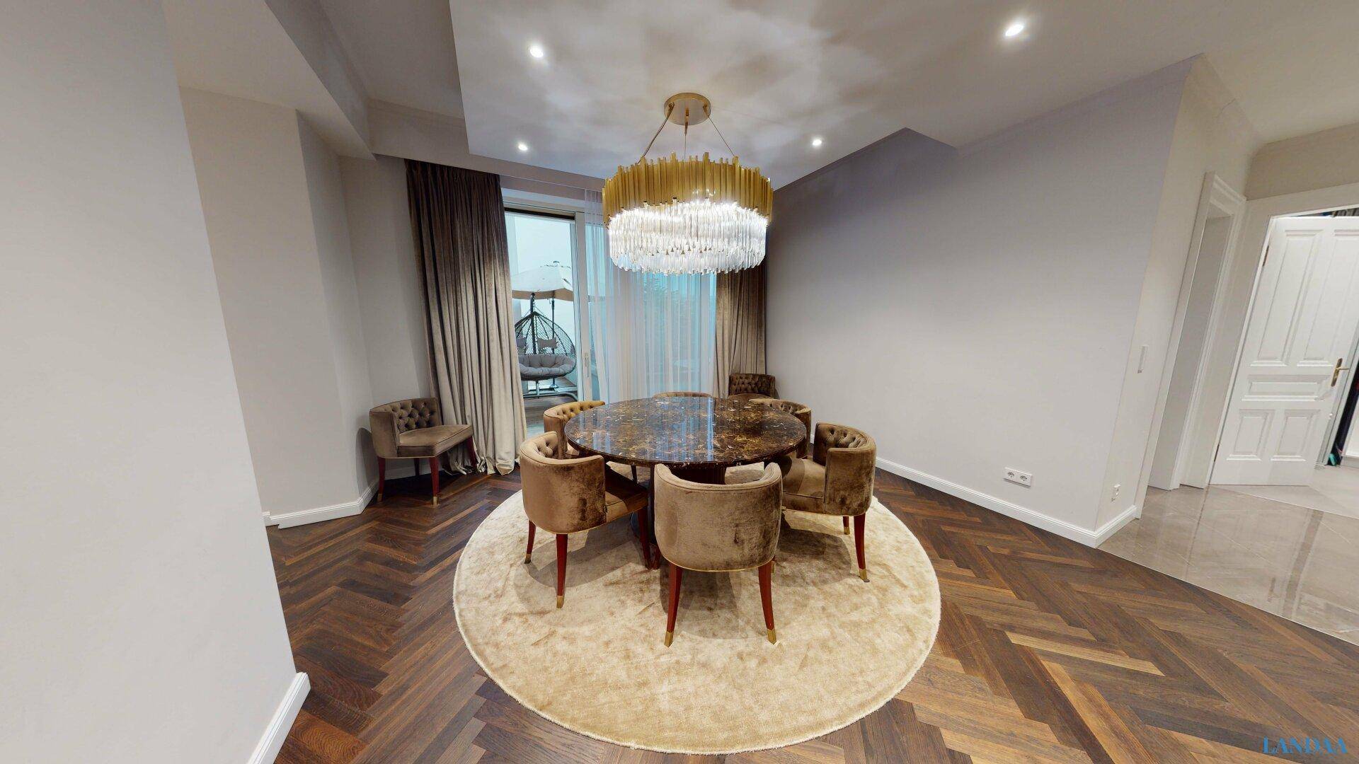Eleganter Essbereich mit rundem Marmortisch, luxuriösem Kronleuchter und Parkettboden.
