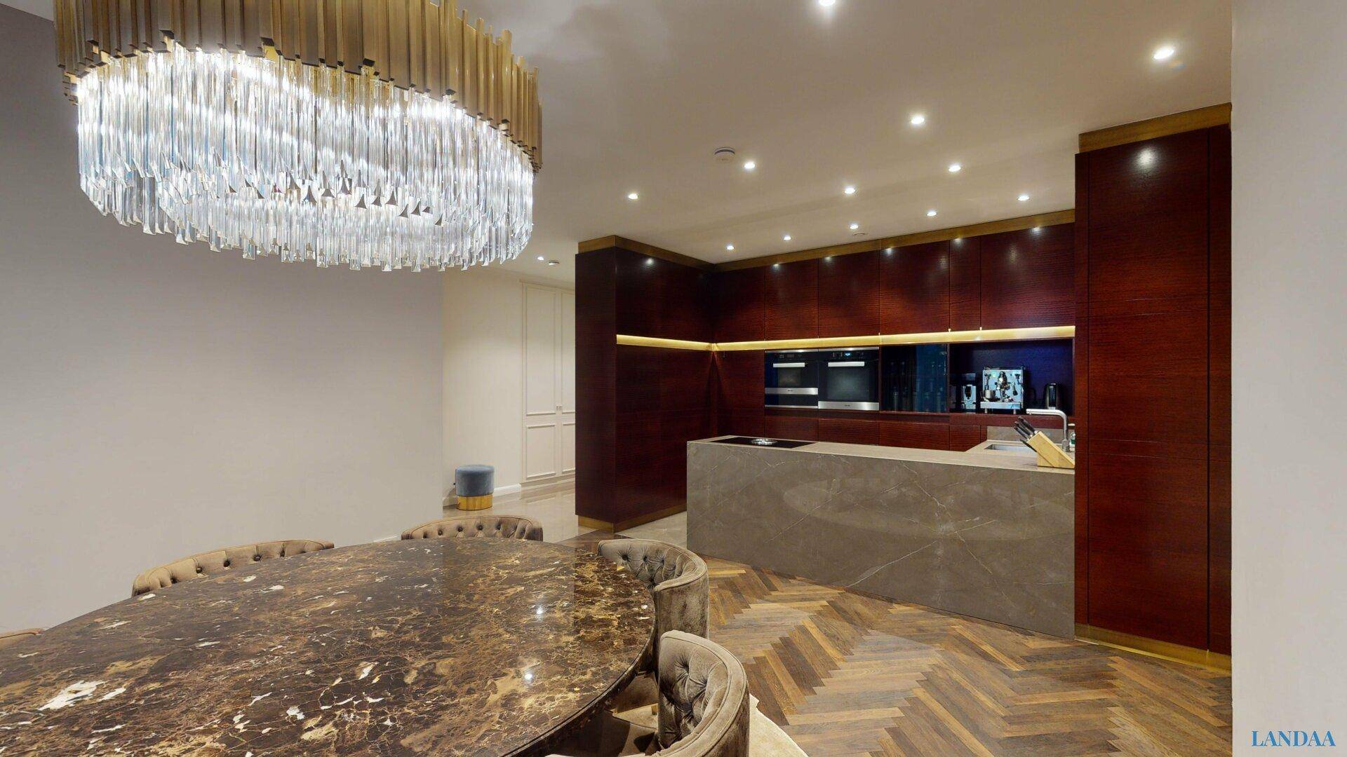 Moderne Küche mit Kochinsel, dunklen Holzfronten, integrierten Geräten und Essbereich.