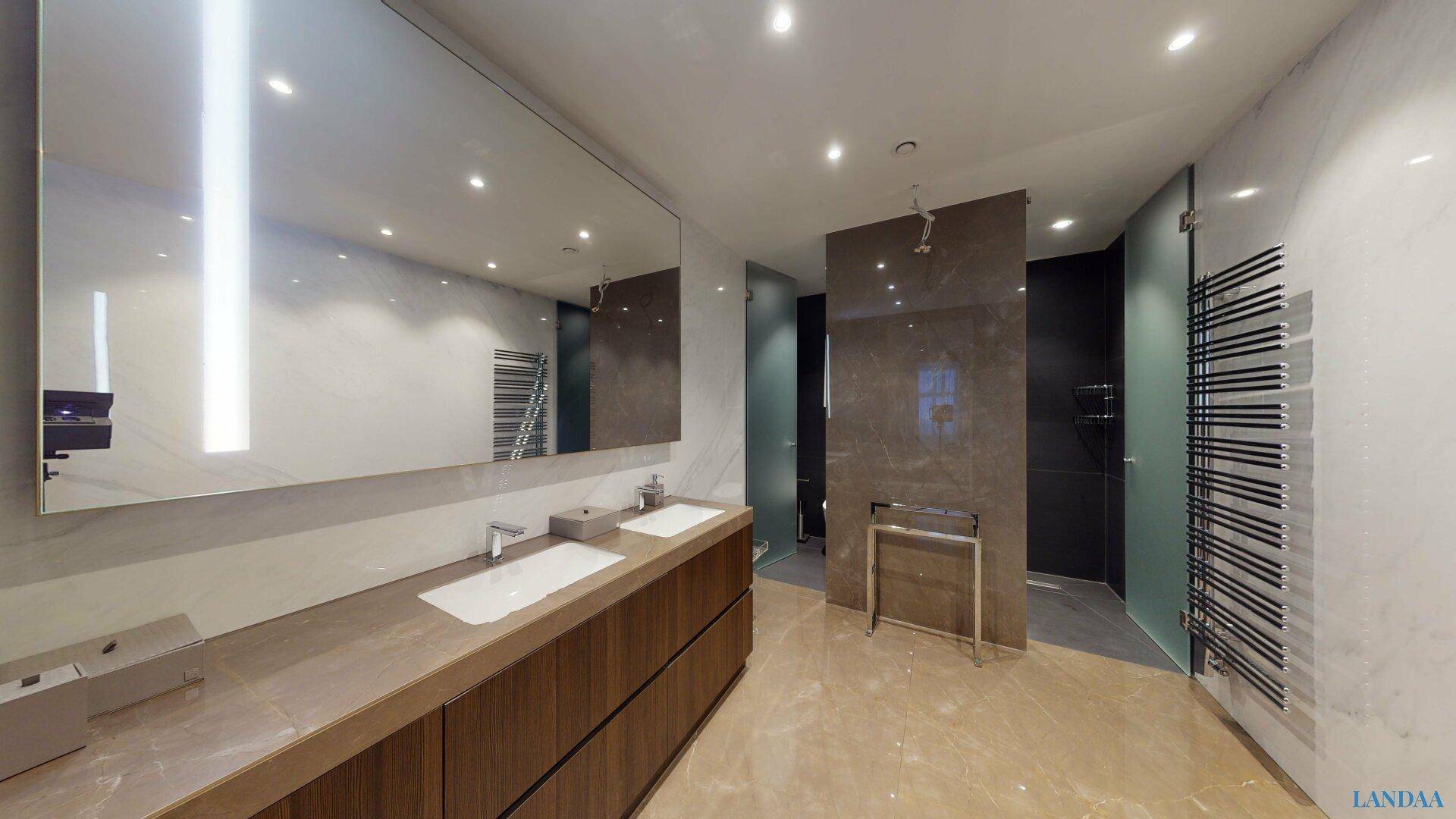 Modernes Badezimmer mit Doppelwaschbecken, großem Spiegel, begehbarer Dusche und Marmorfliesen.