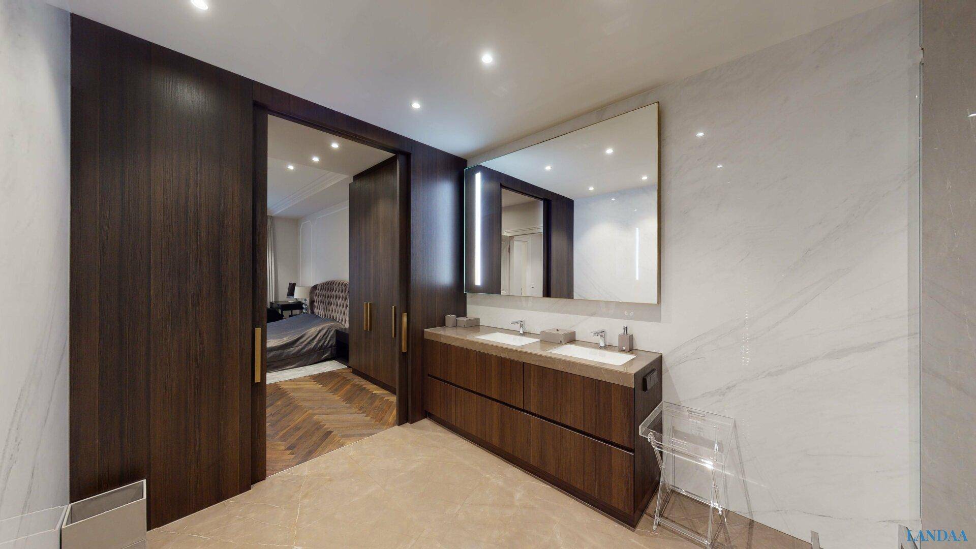 Luxuriöses Ensuite-Badezimmer mit Doppelwaschbecken, großem Spiegel und direktem Zugang zum Schlafzimmer.