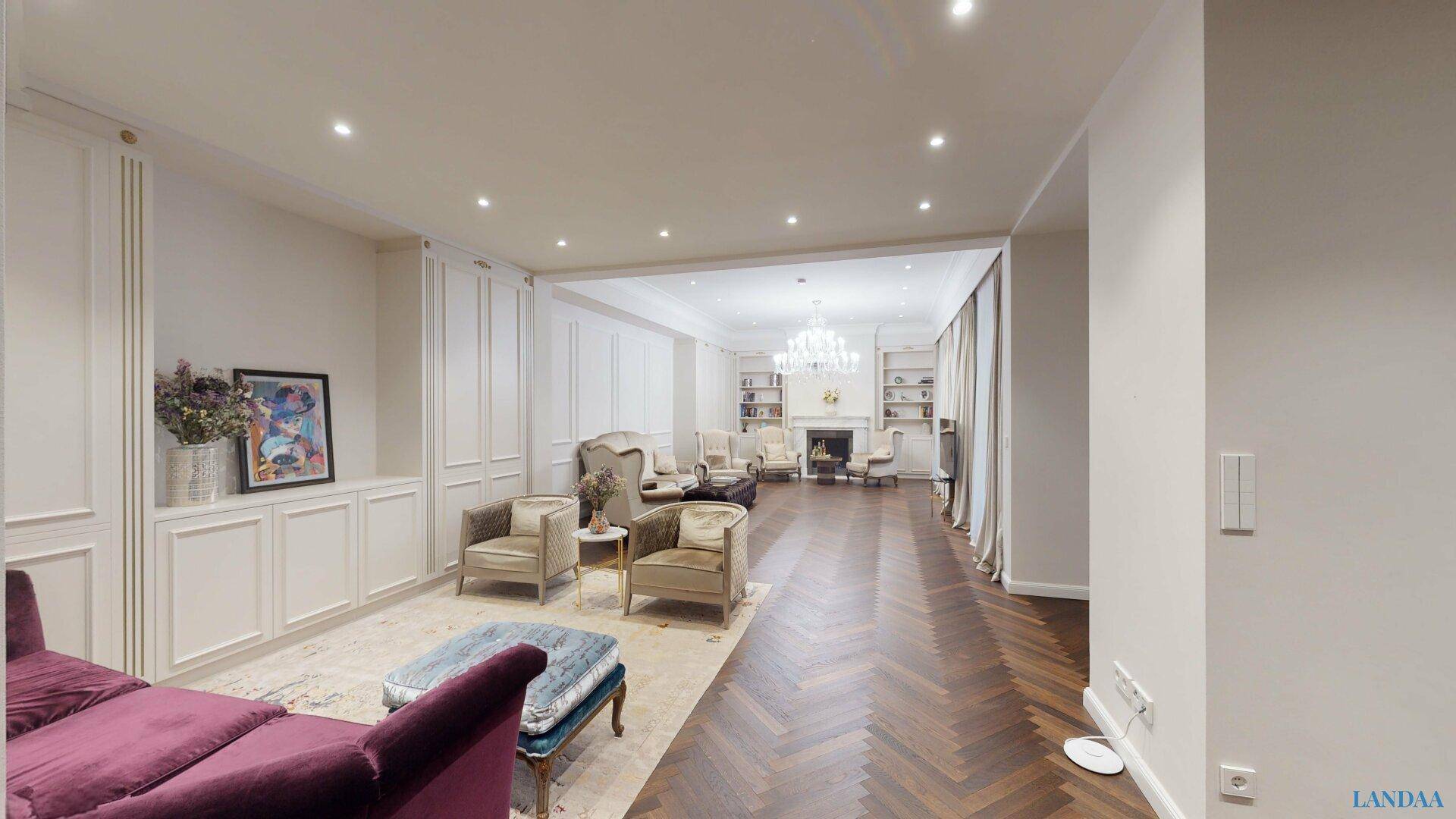 Weitläufiger Wohnbereich mit elegantem Fischgrätparkett, hohen Decken und klassischer Einrichtung.