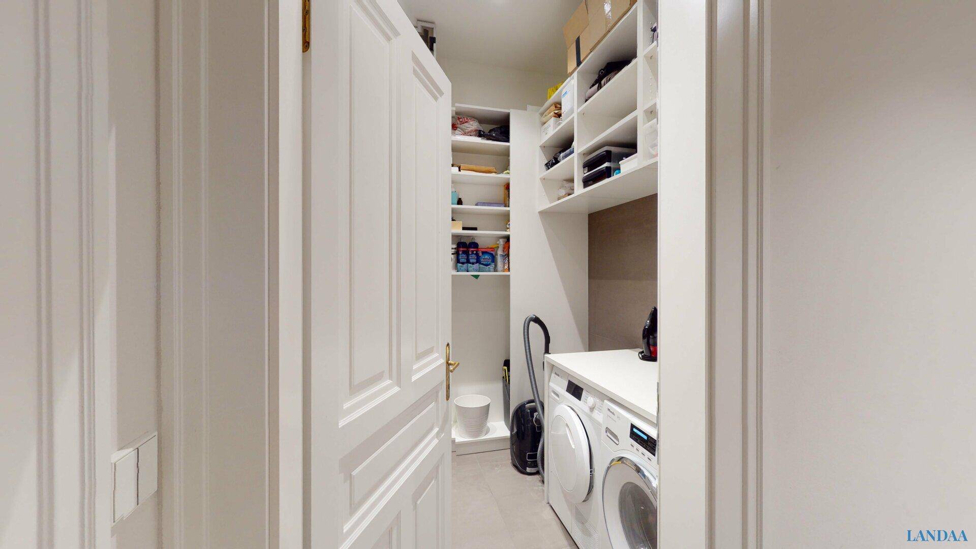 Praktischer Hauswirtschaftsraum mit Waschmaschine, Trockner und Regalen für zusätzlichen Stauraum.