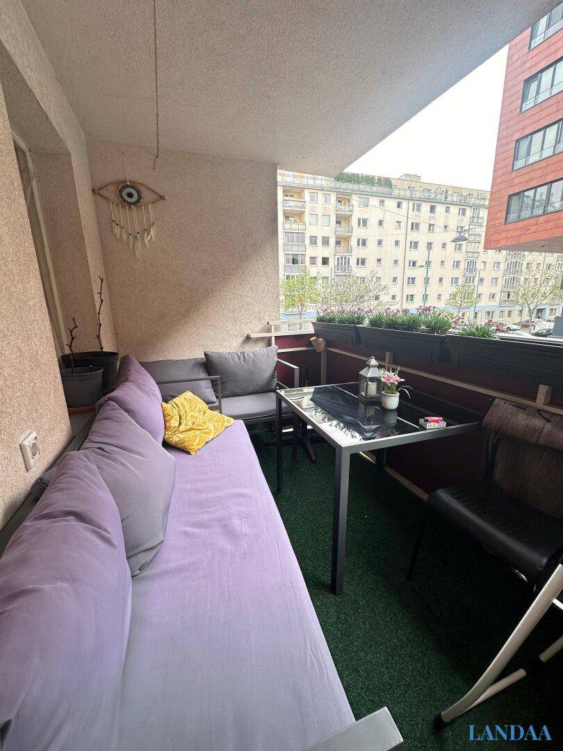 Gemütlicher Balkon mit Sitzgelegenheiten, Pflanzen und Blick auf die Stadt.