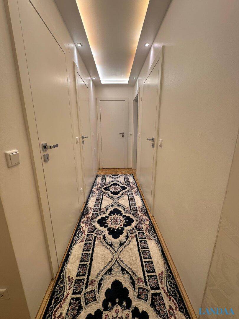 Langer Flur mit Parkettboden, Einbauschränken und moderner Deckenbeleuchtung.