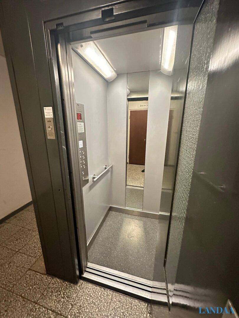 Moderner Aufzug in einem Wohngebäude mit Spiegelfläche und Edelstahl-Elementen.