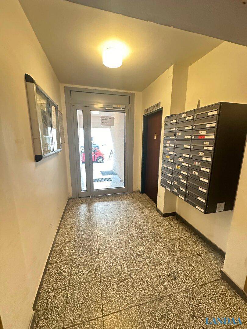 Eingangsbereich eines Wohngebäudes mit Briefkästen und Zugang zur Straße.