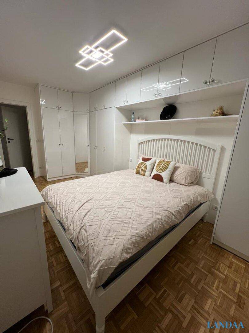 Helles Schlafzimmer mit großem Bett, weißen Einbauschränken und Parkettboden.
