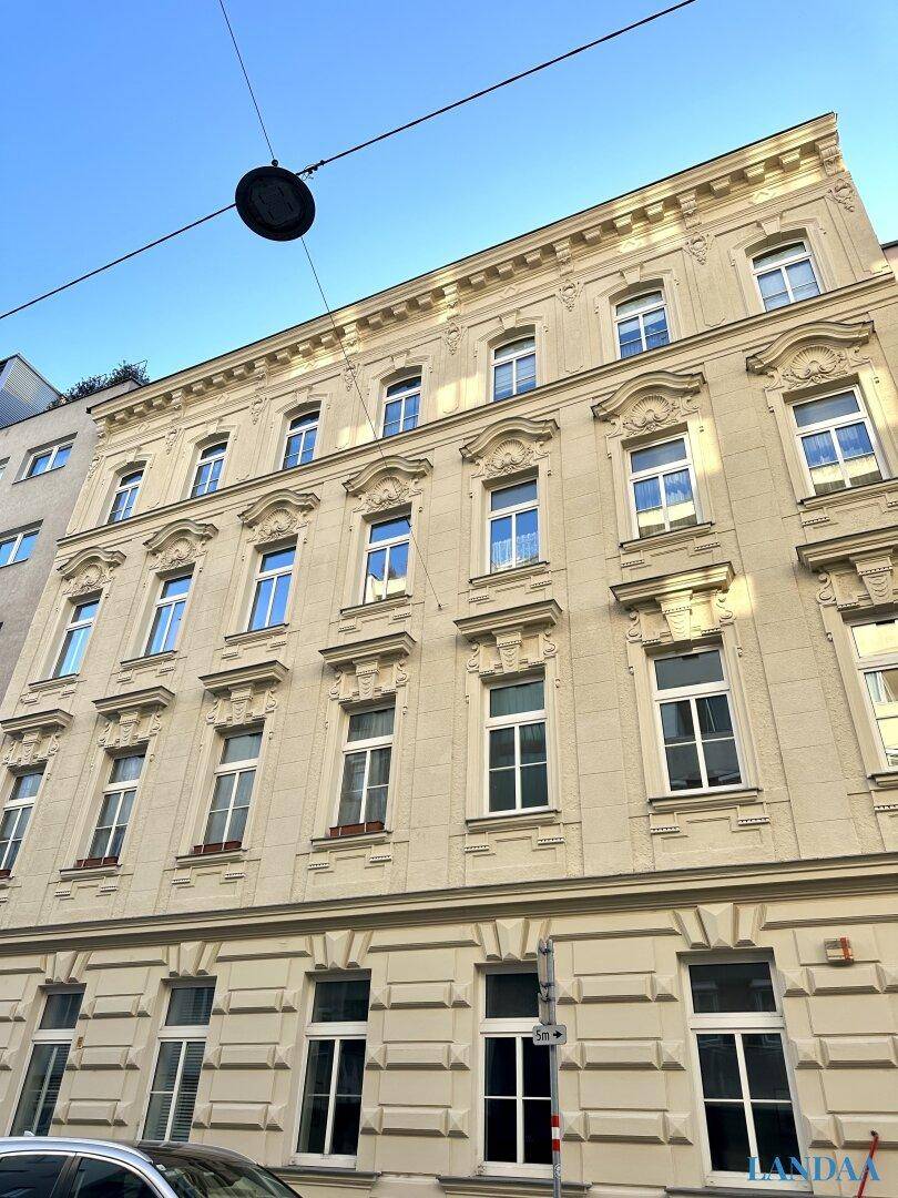 Klassische Fassade eines Altbaus mit vielen Fenstern und dekorativen Elementen.
