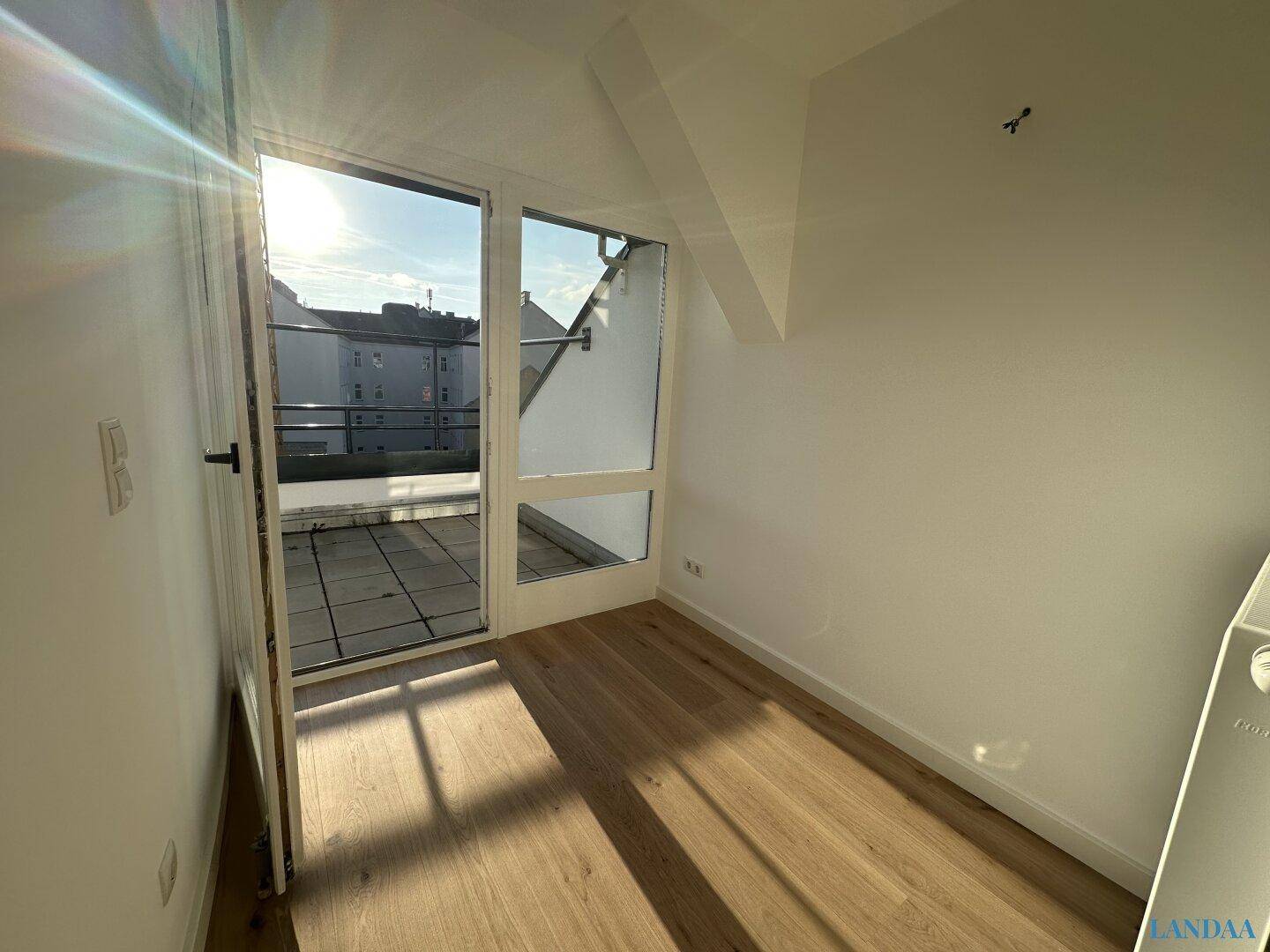 Heller Raum mit Holzboden und direktem Zugang zu einer sonnigen Terrasse.