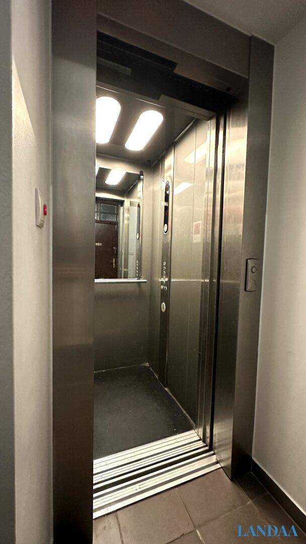Moderner Aufzug mit Edelstahloberflächen und geöffneten Türen in einem Gebäude.