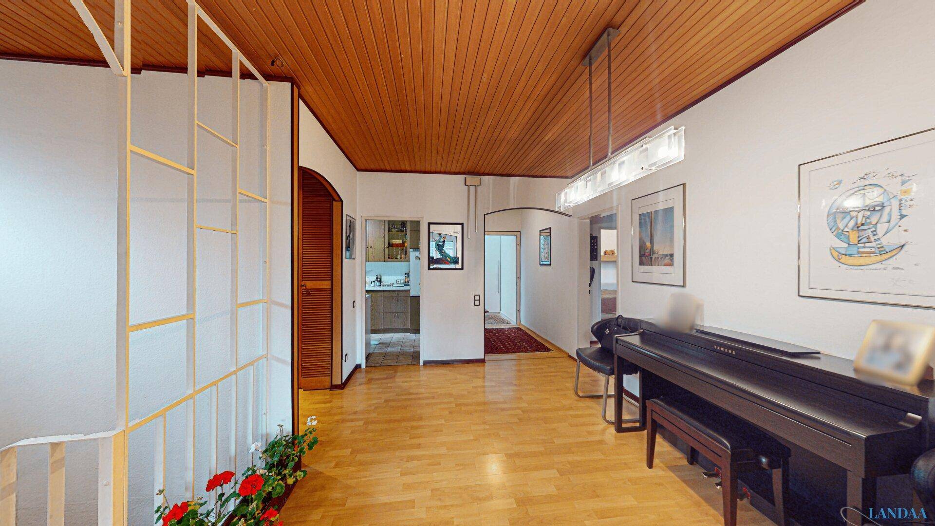 Heller Flur mit Holzdeckenverkleidung, Parkettboden und einem Klavier, der verschiedene Bereiche verbindet.