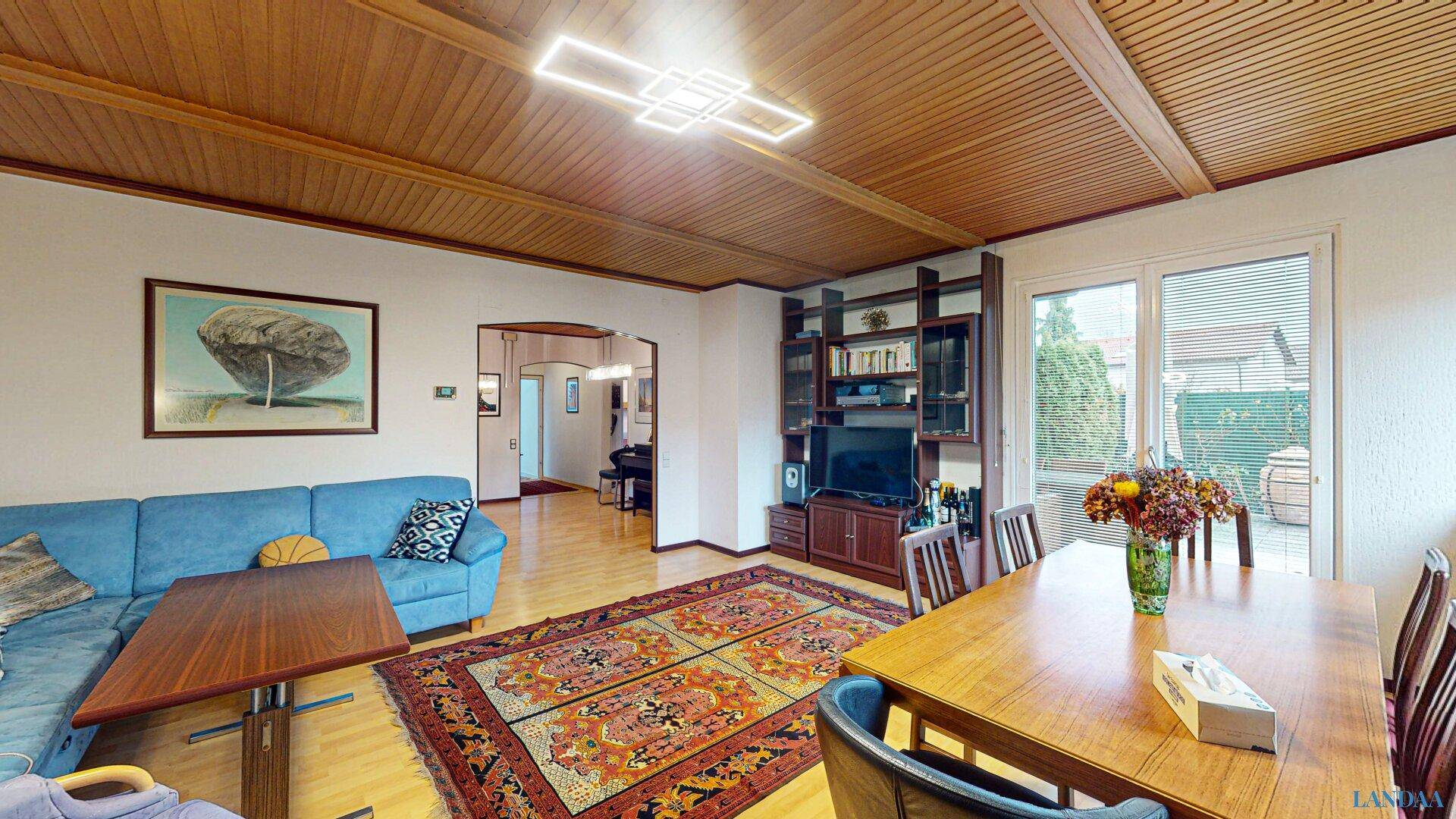 Geräumiger Wohn-Essbereich mit Holzdeckenverkleidung, Parkettboden und Zugang zur Terrasse.