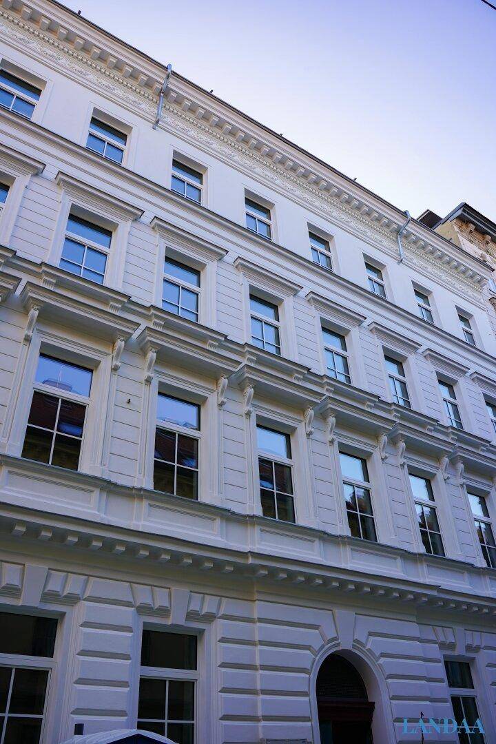 Historische Fassade eines eleganten Gebäudes mit vielen Fenstern und Stuckverzierungen.