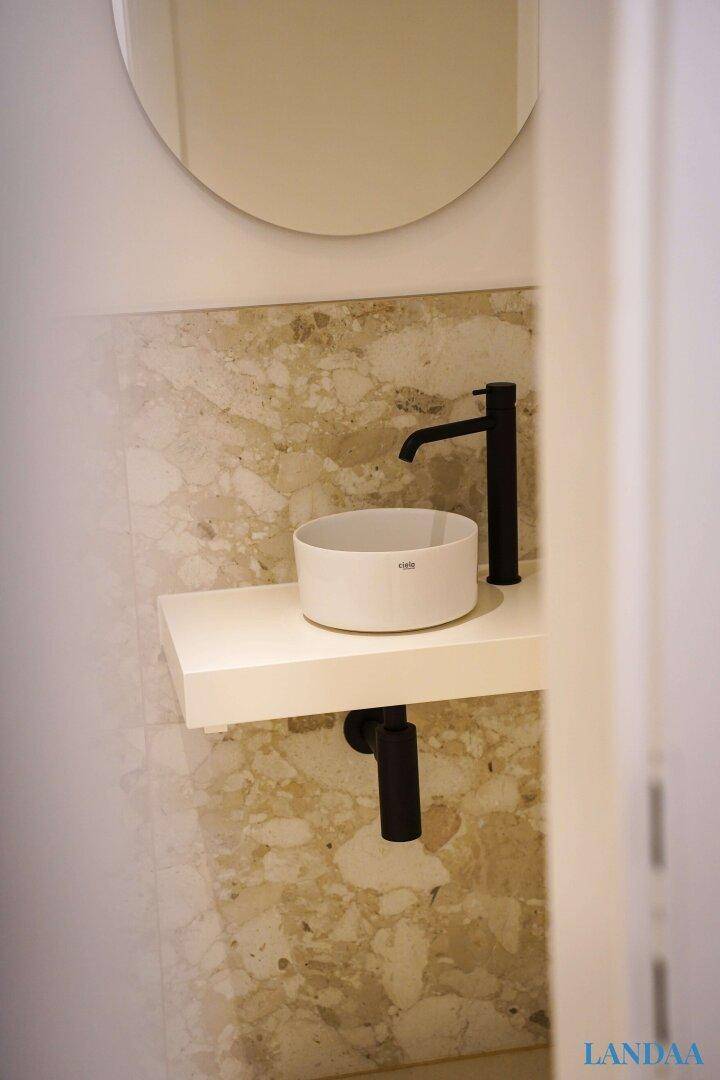 Modernes Gäste-WC mit Aufsatzwaschbecken, schwarzem Wasserhahn und Marmorfliesen.