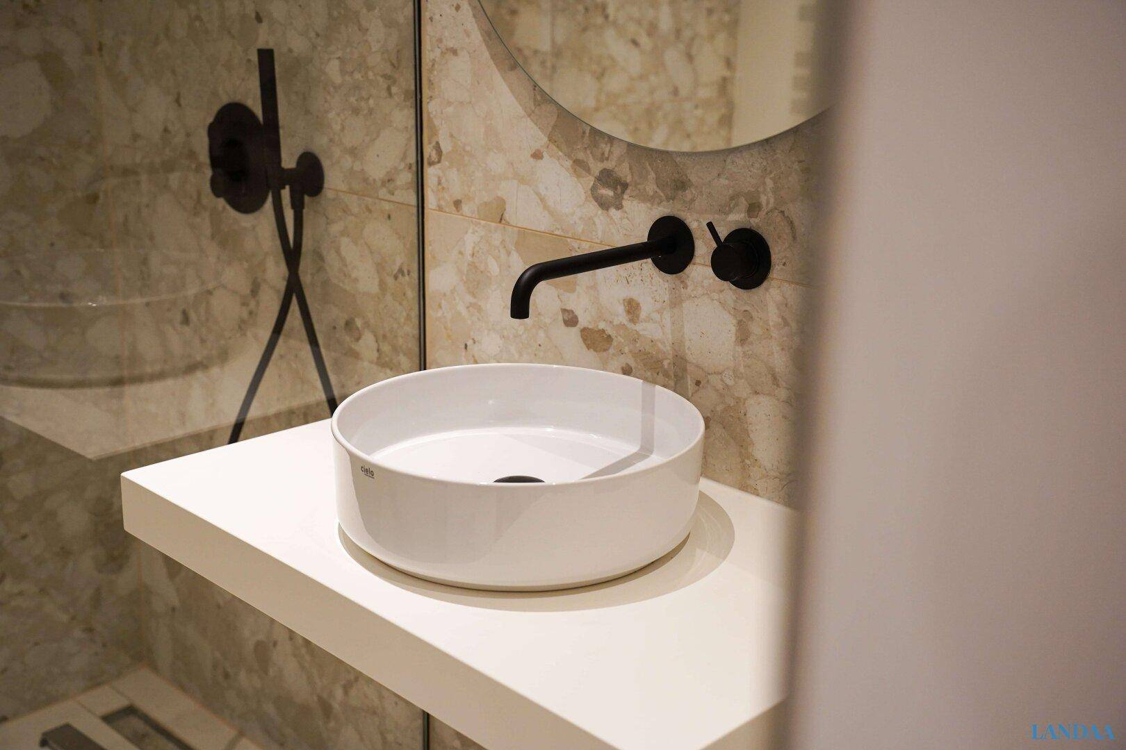 Modernes Badezimmer mit Aufsatzwaschbecken, schwarzem Wasserhahn und Marmorfliesen.