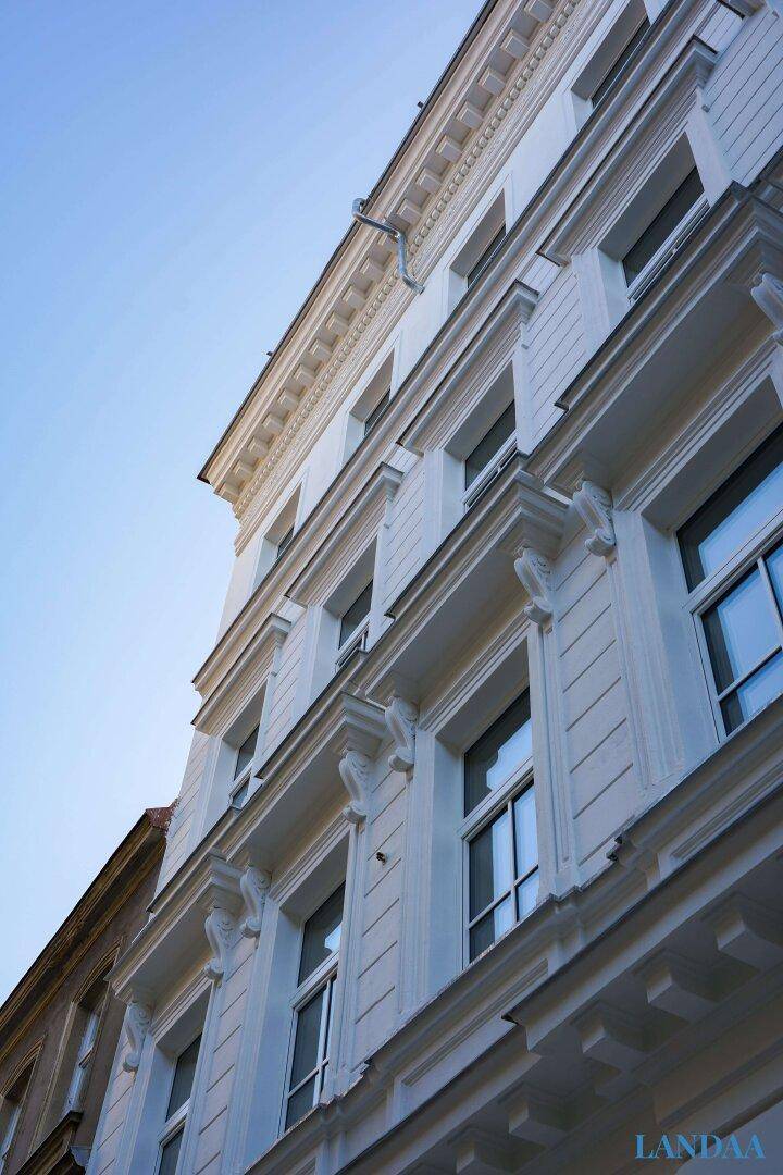 Historisches Gebäude mit weißer Fassade, vielen Fenstern und klassischen architektonischen Details.