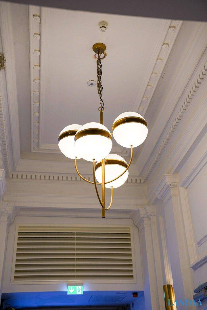 Elegante Deckenleuchte mit vier Kugeln und Stuckverzierungen an der hohen Decke.
