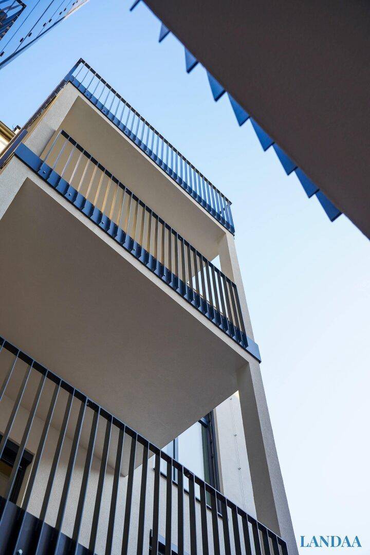 Moderne Balkone mit schwarzen Geländern an der Fassade eines Wohngebäudes.