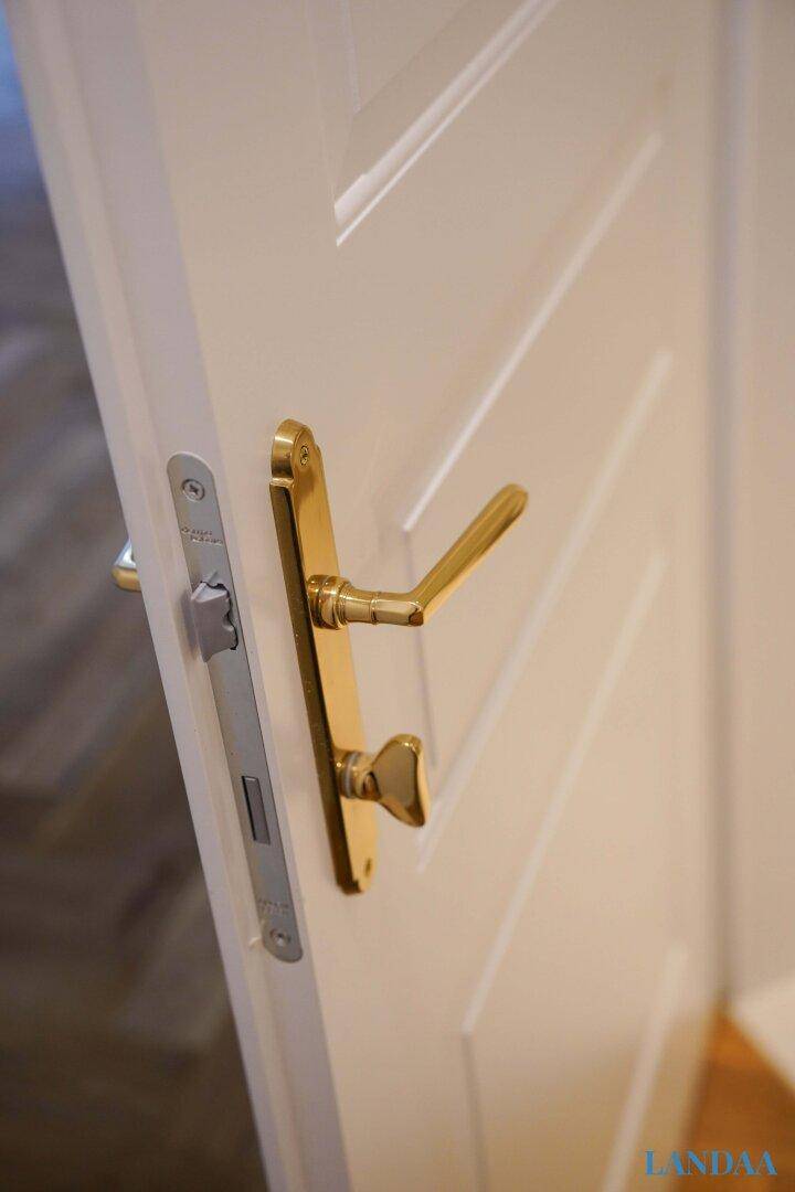 Elegante goldene Türgriffe an einer weißen Innentür, die den klassischen Stil unterstreichen.