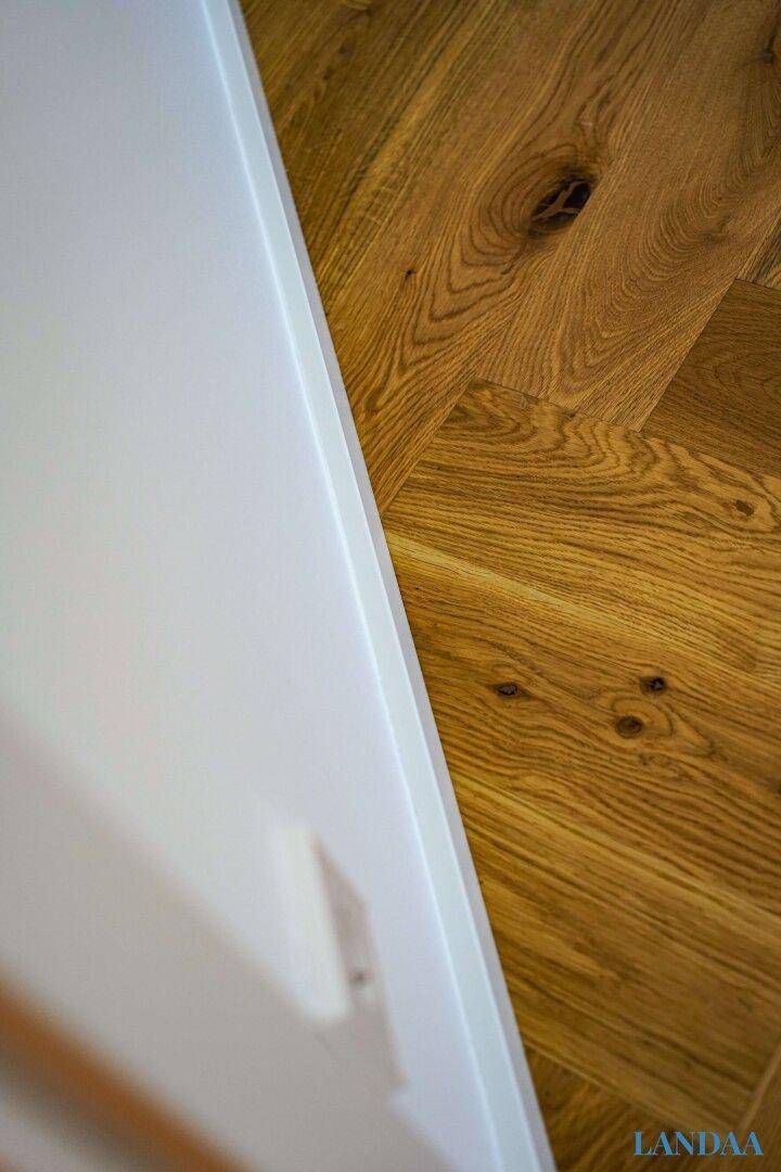 Detailaufnahme von hochwertigem Fischgrätparkett und sauberer weißer Fußleiste.