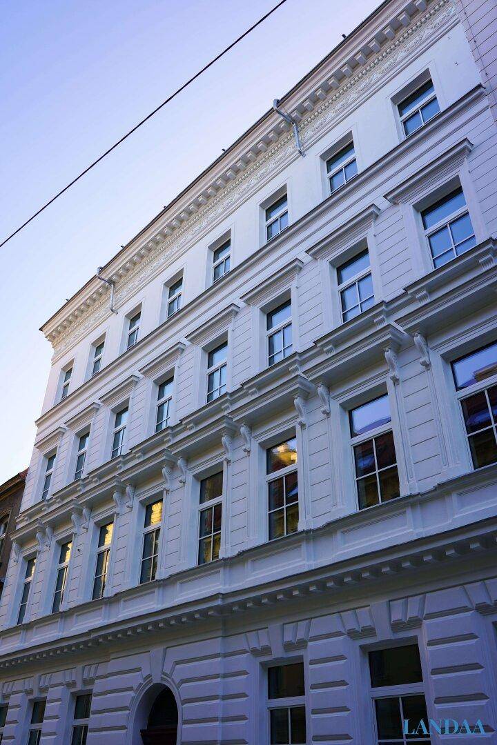 Elegante weiße Fassade eines historischen Gebäudes mit vielen Fenstern und Verzierungen.