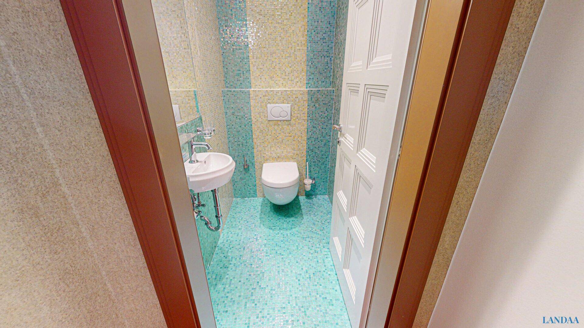 Farbenfrohes Gäste-WC mit blauen und gelben Mosaikfliesen und wandhängendem WC.