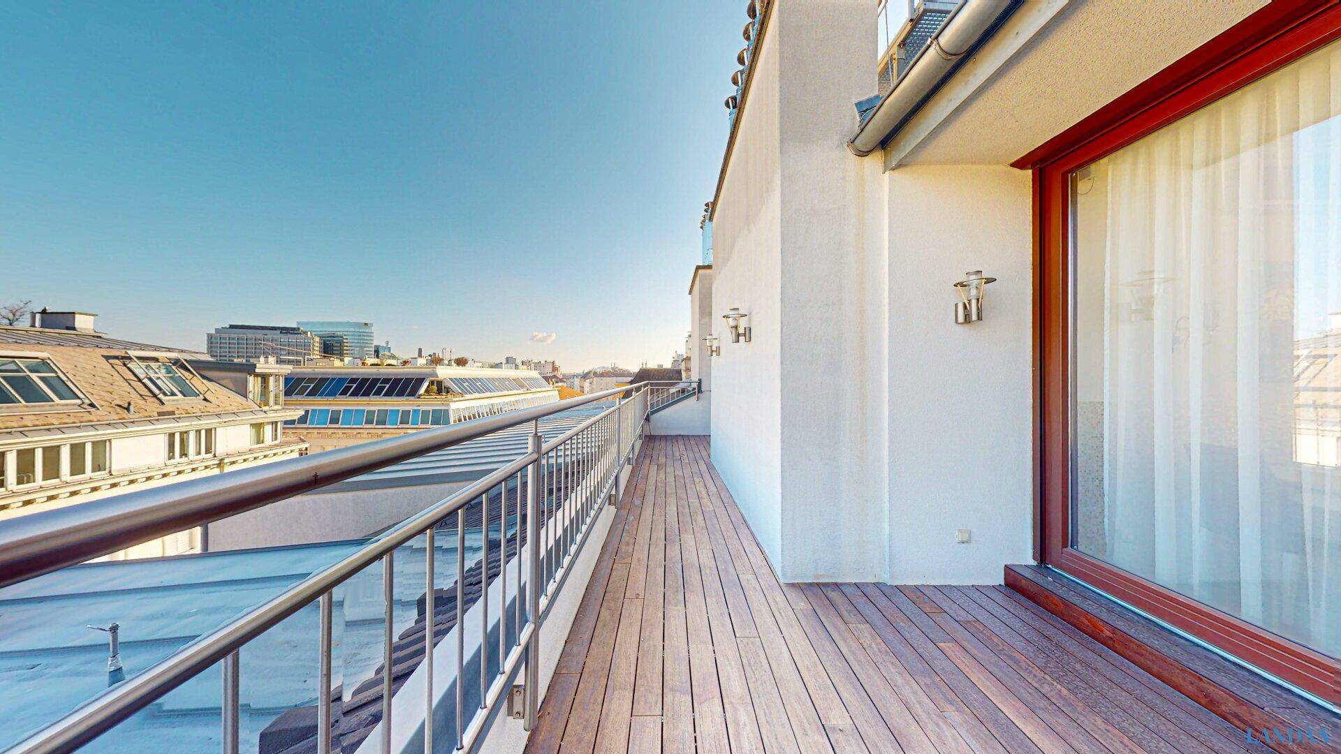 Lange Dachterrasse mit Holzboden und weitem Blick über die Dächer der Stadt.