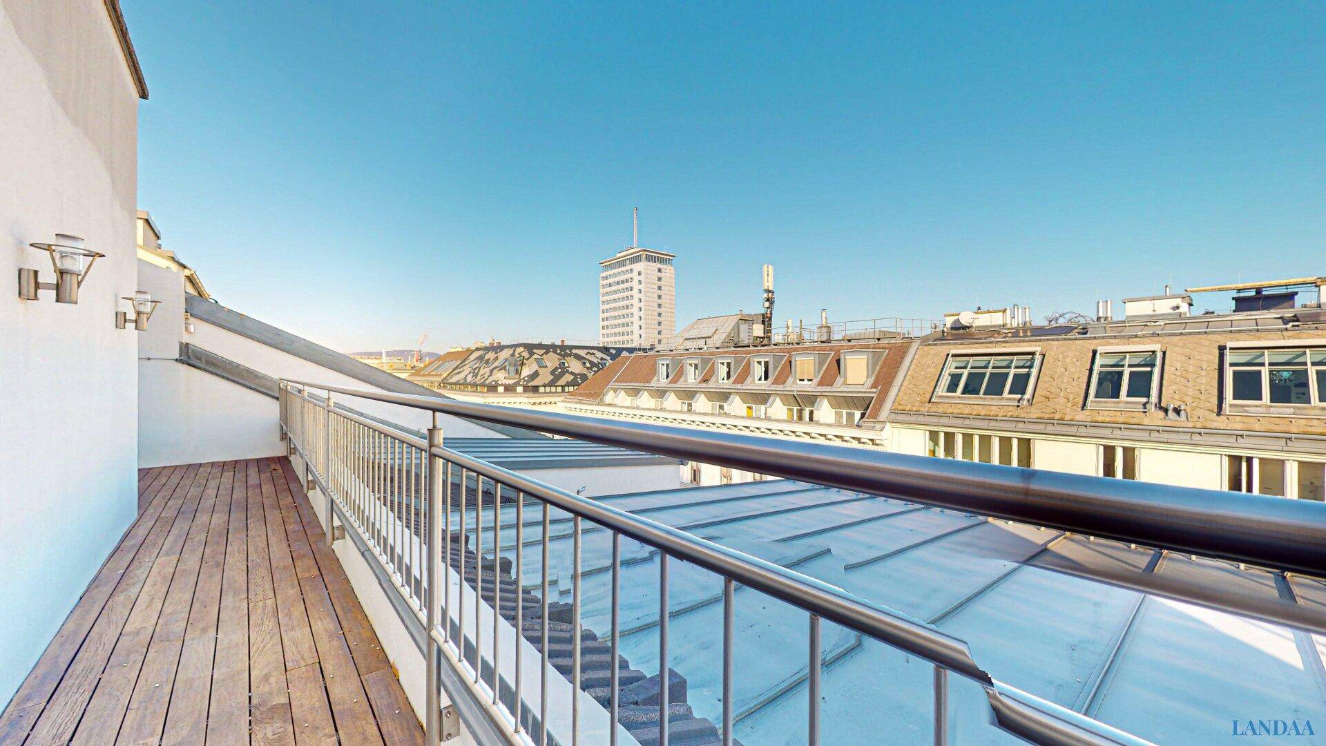 Sonnige Dachterrasse mit Holzboden und Panoramablick auf die städtische Skyline.