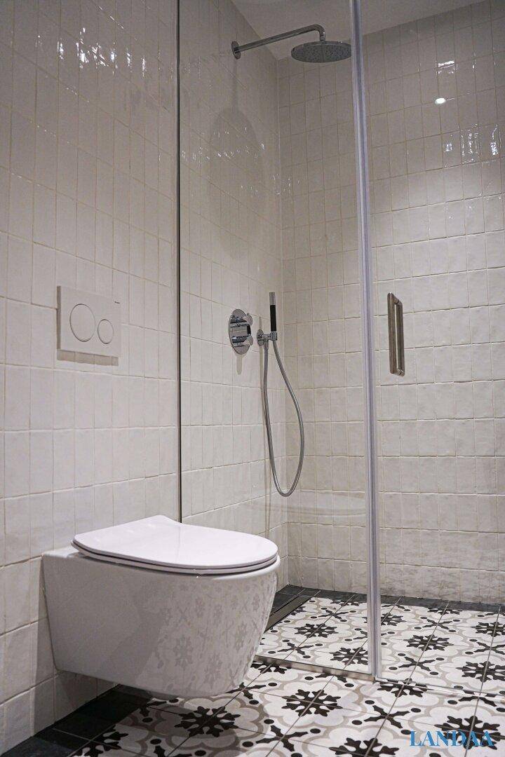 Wandhängendes WC mit Spülkasten und dekorativen Bodenfliesen im modernen Badezimmer.