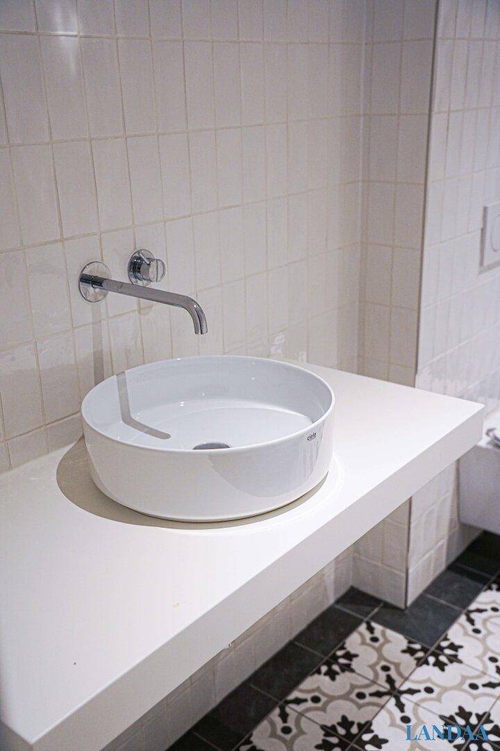 Modernes Aufsatzwaschbecken auf einer weißen Ablage mit Wandarmatur im Badezimmer.