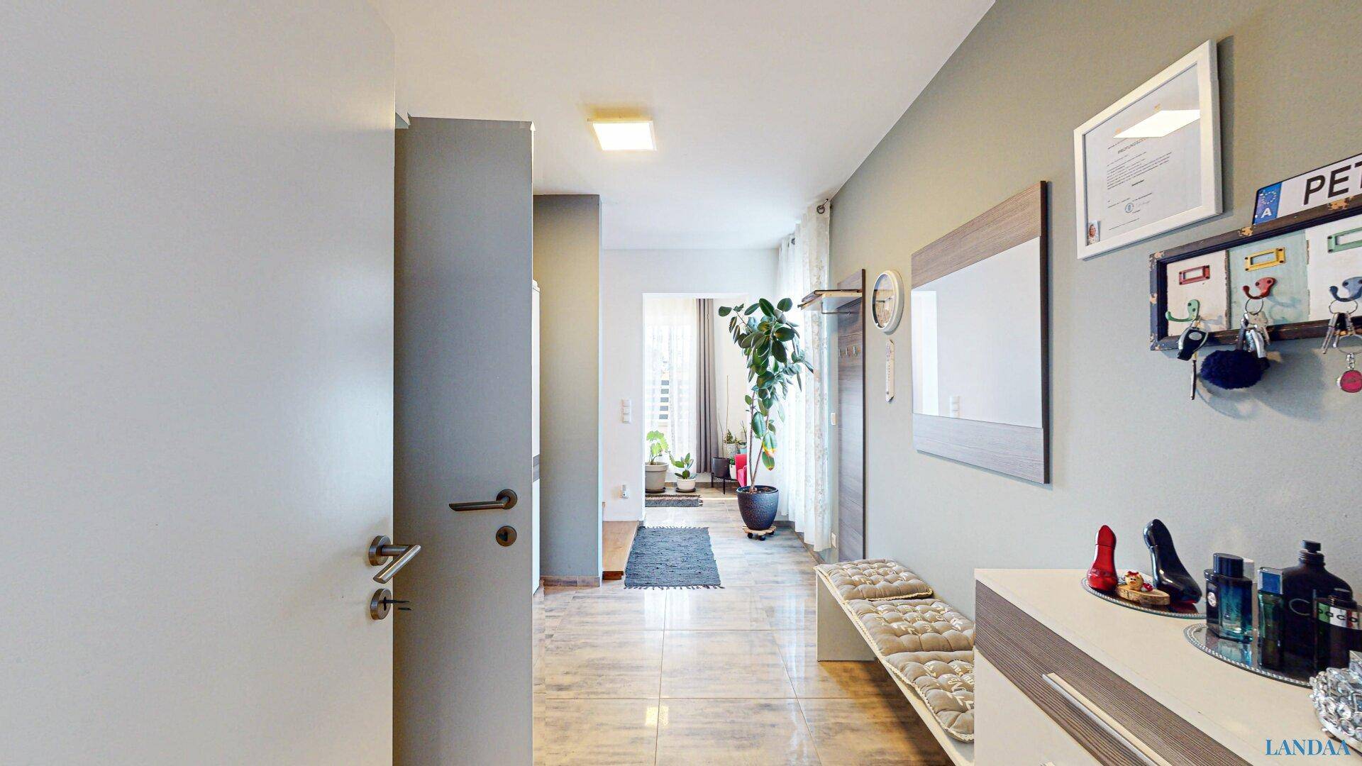 Heller Eingangsbereich mit Fliesenboden, Garderobe und modernem Dekor.