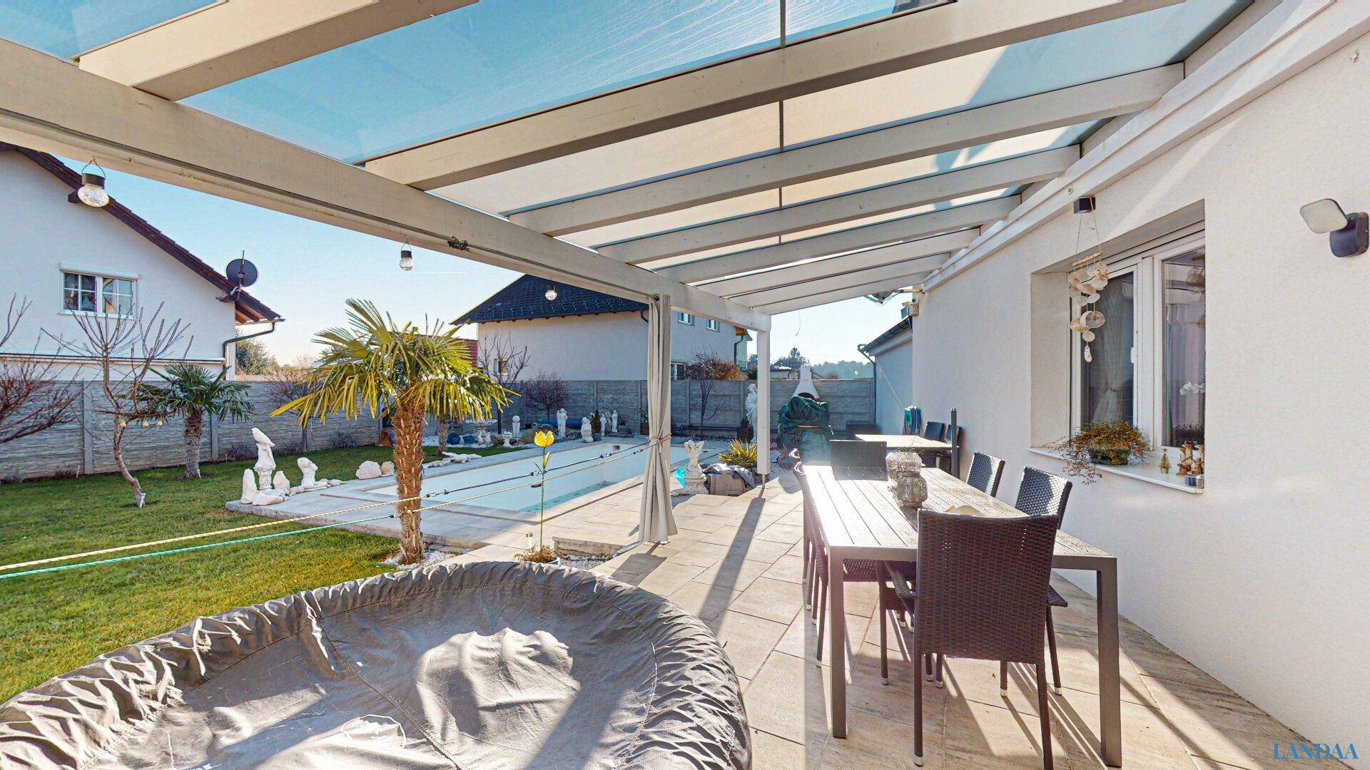 Überdachte Terrasse mit Essbereich im Freien, Whirlpool und Blick auf den Garten.