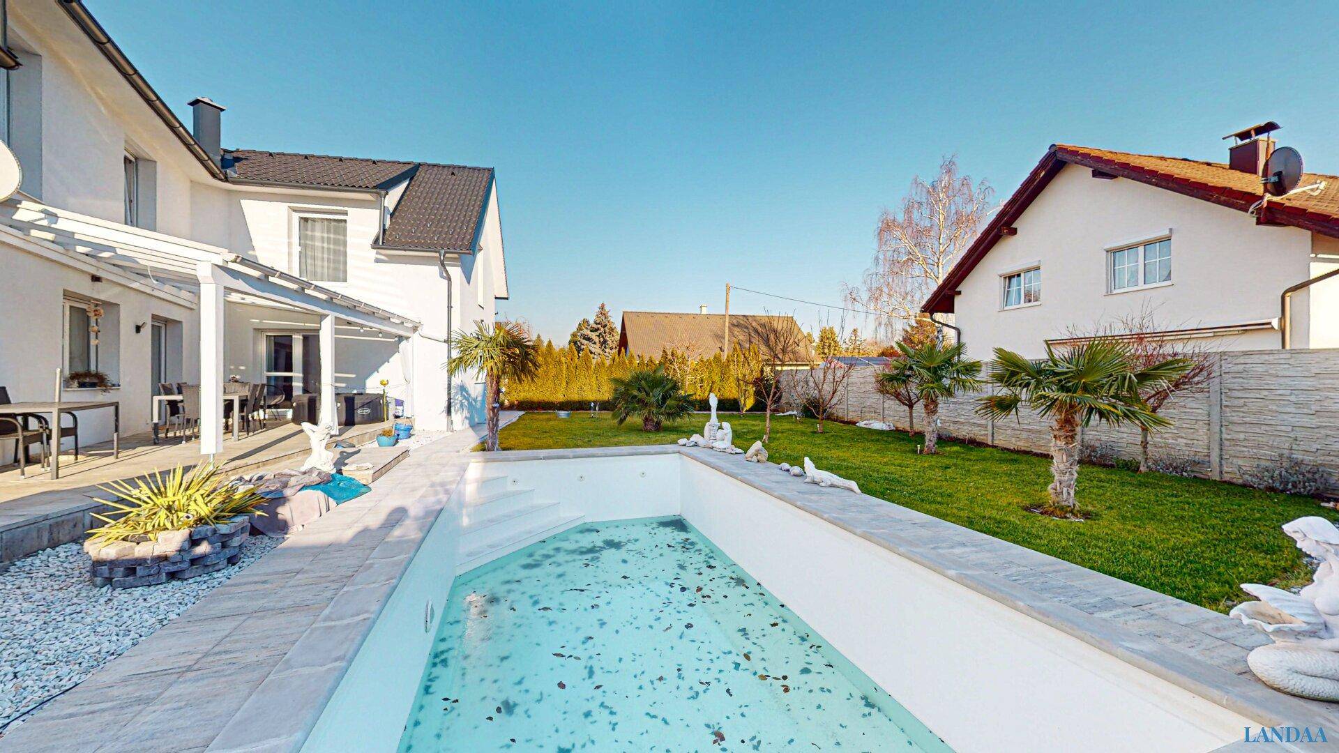 Gepflegter Gartenbereich mit großem Pool und umliegender Grünfläche.