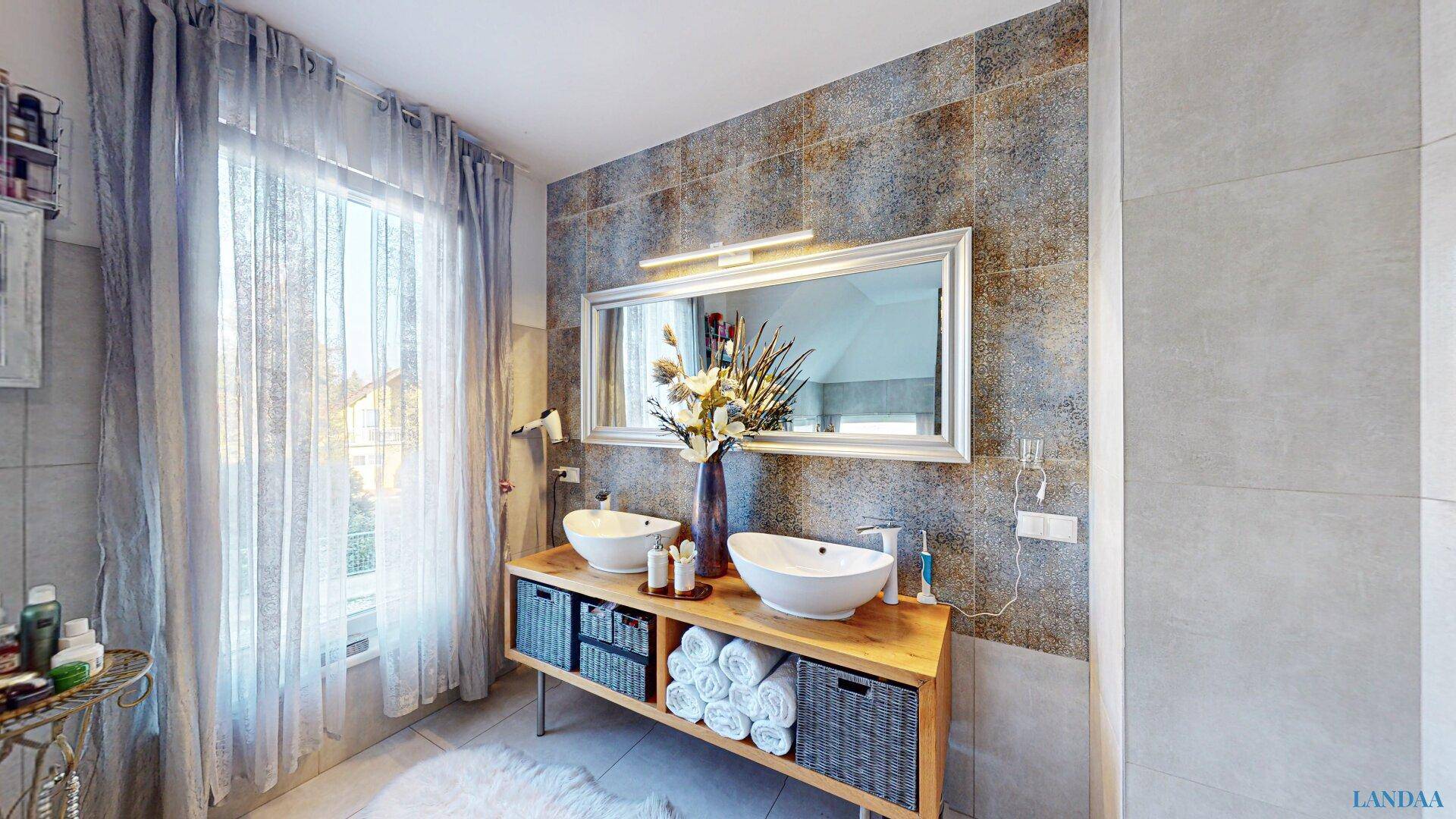 Modernes Badezimmer mit Doppelwaschbecken, großem Spiegel und Fenster.