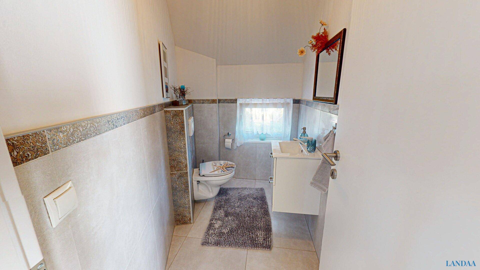 Kleines Gäste-WC mit Fenster, Waschbecken und Wand-WC.