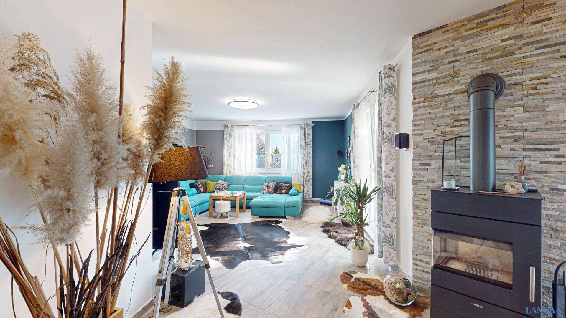 Gemütliches Wohnzimmer mit Kaminofen, Steinwand und großem Ecksofa in Türkis.