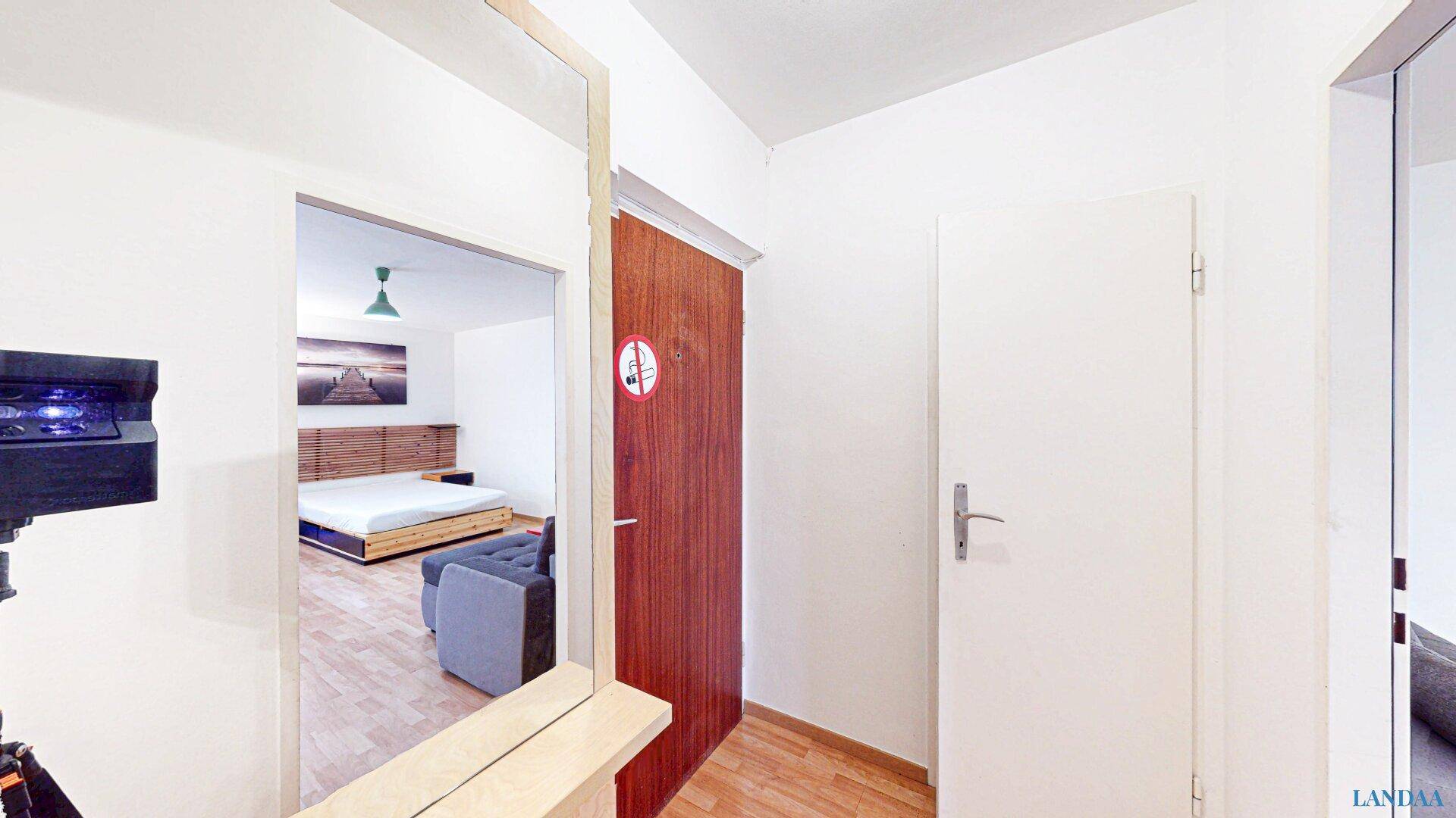 Flur mit Holztür und einem Blick in den hellen, offenen Wohnbereich der Wohnung.