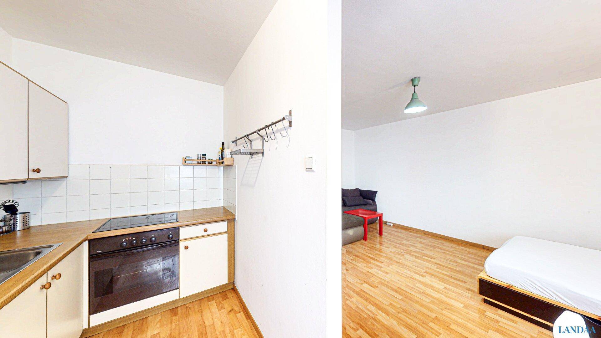 Kompakte Küche mit weißen Schränken und Blick in den angrenzenden Wohnbereich.