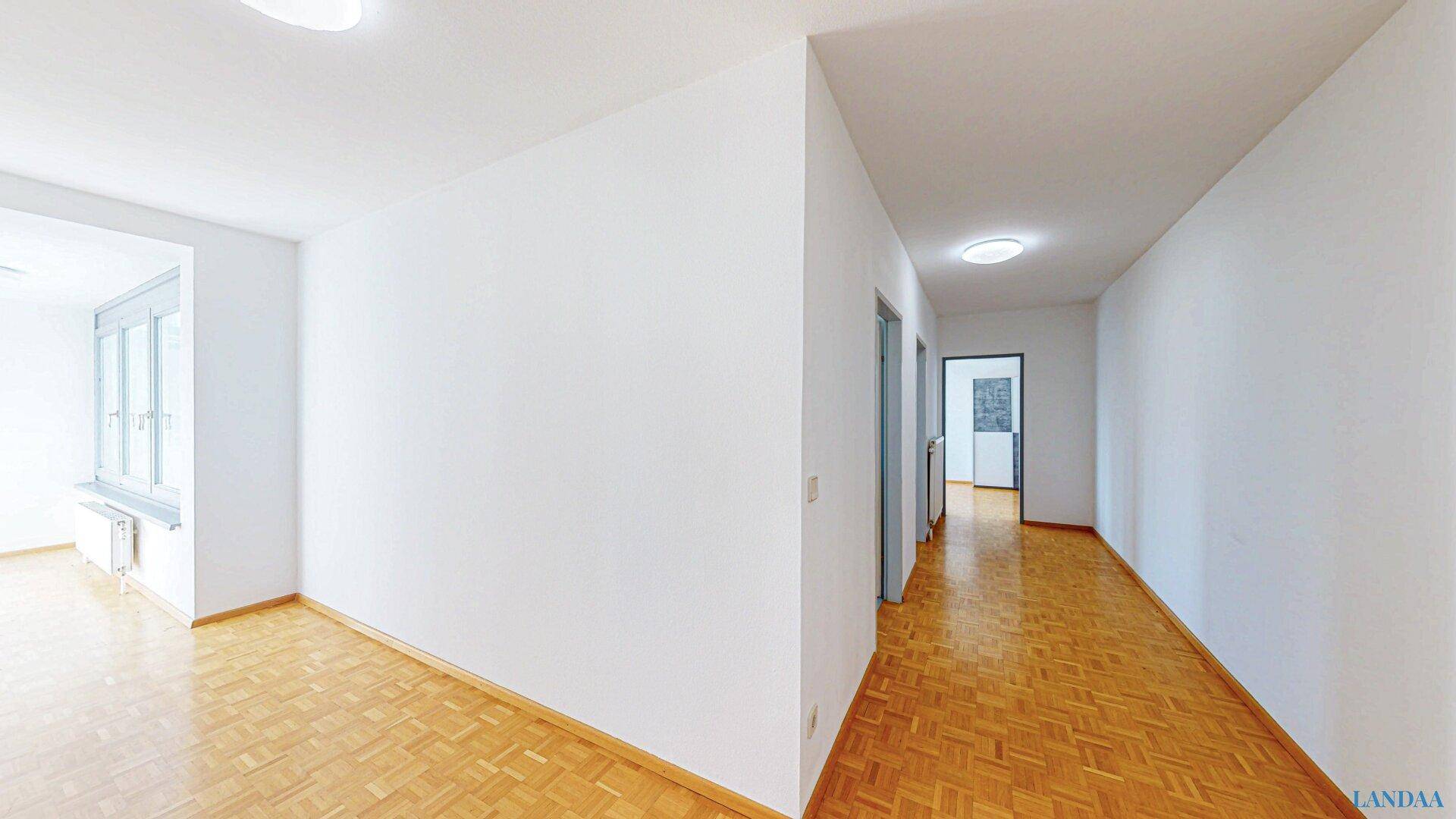 Langer, heller Flur mit Parkettboden und Zugang zu verschiedenen Räumen.