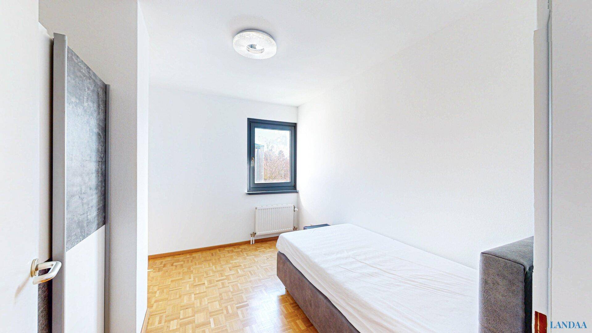 Kleineres Schlafzimmer mit Parkettboden, Einzelbett und Fenster.