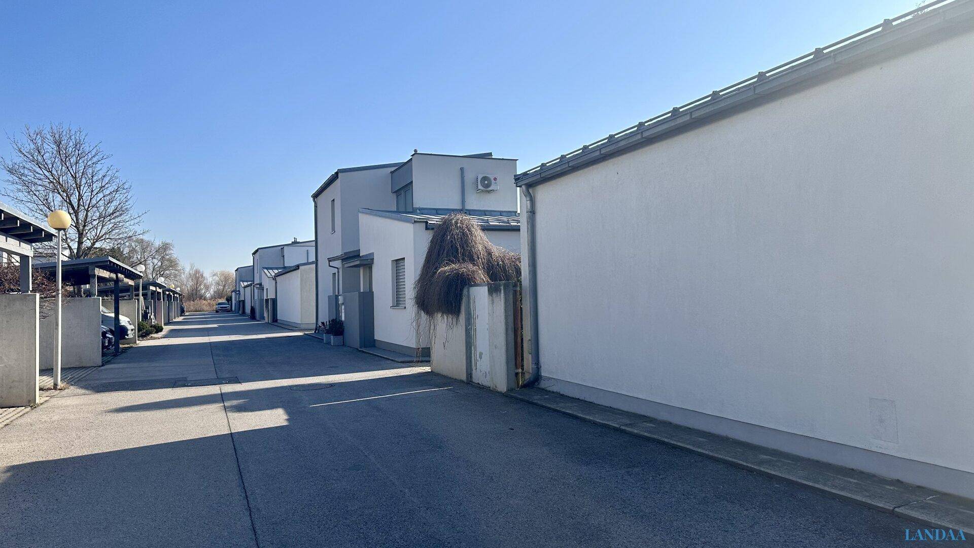 Blick auf die ruhige Wohnstraße mit modernen Reihenhäusern und Carports.